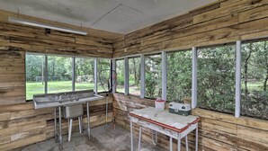 A rustic kitchen with wooden walls, large windows, and a sink. - Waterfront Sopchoppy Hideaway w/ 2 Kayaks! (Sopchoppy)