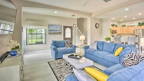 A spacious living area with a blue sofa set, a coffee table, and a zebra-patterned rug. - Disney Villa w/ Game Room & Pool - 10 Mi to Parks! (Clermont)