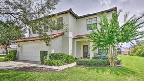 A two-story house with a white exterior, a red-tiled roof, and a garage. - Disney Villa w/ Game Room & Pool - 10 Mi to Parks! (Clermont)