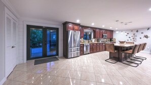 Una cocina moderna con una isla grande, electrodomésticos de acero inoxidable y una zona de comedor con una mesa alta y sillas.