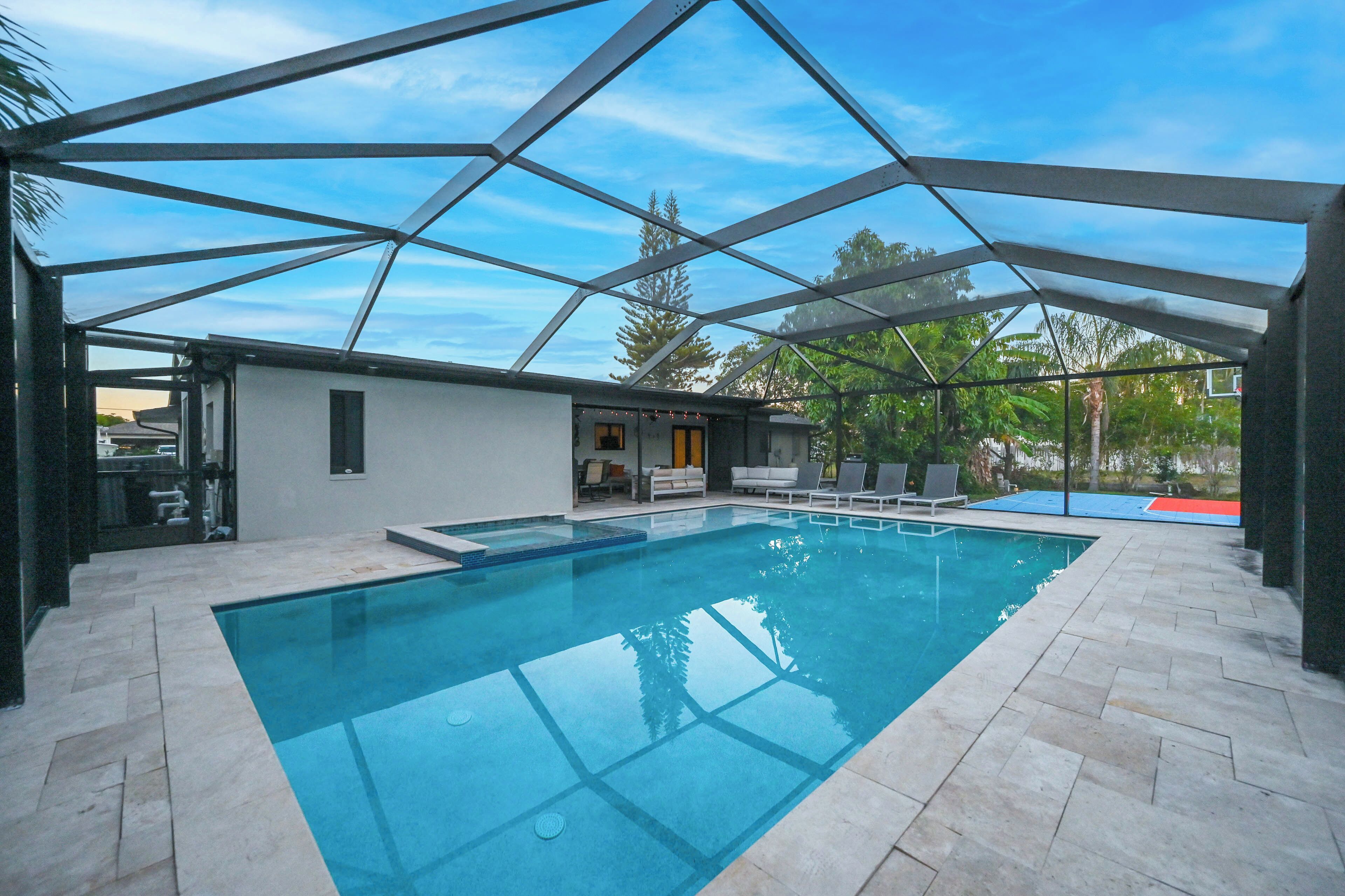 Ein Innenpool mit geometrischem Glasdach, umgeben von einer Terrasse mit Liegestühlen und einer kleinen Sitzecke.