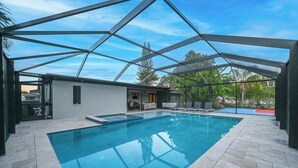 Una piscina interior con techo de vidrio geométrico, rodeada por un patio con sillones de descanso y una pequeña zona de estar.