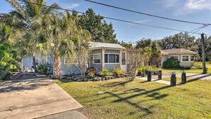 A single-story house with a sloped roof, a front porch, and a small garden with palm trees and shrubs. - Tropical Port Charlotte Cottage - Walk to Bay! (Punta Gorda)