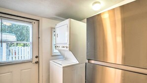 A laundry room with a front-loading washer and dryer, a stainless steel refrigerator, and a door with a window. - Tropical Port Charlotte Cottage - Walk to Bay! (Punta Gorda)