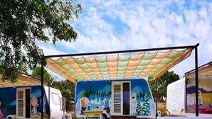 A caravan park with multiple caravans, a paved walkway, and a shaded area. - Bahile (Liuqiu)
