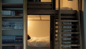 A bunk bed with a wooden ladder, a bookshelf with books, and a bedside lamp. - HOTEL BOTH - Hostel (Shari)