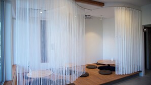A modern interior with a wooden floor, round tables, and a seating area with cushions. - HOTEL BOTH - Hostel (Shari)