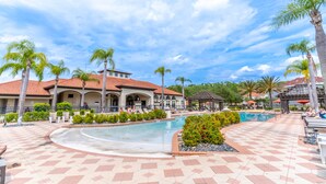 Ein Resort mit Swimmingpool, Palmen und einem gefliesten Weg.