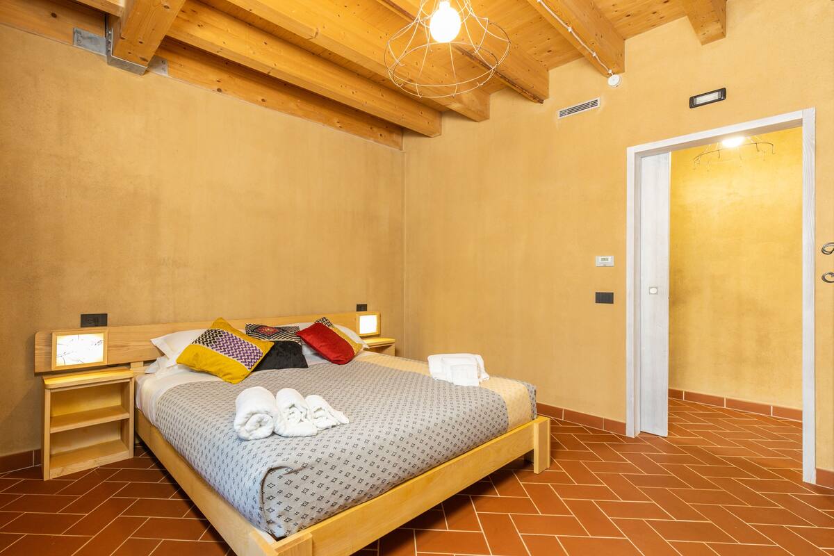 A bedroom with a wooden bed, a nightstand, a bedside table, and a door.
