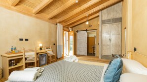 Una habitación de hotel con una cama grande, vigas de madera en el techo, un escritorio con silla, televisión y un armario.