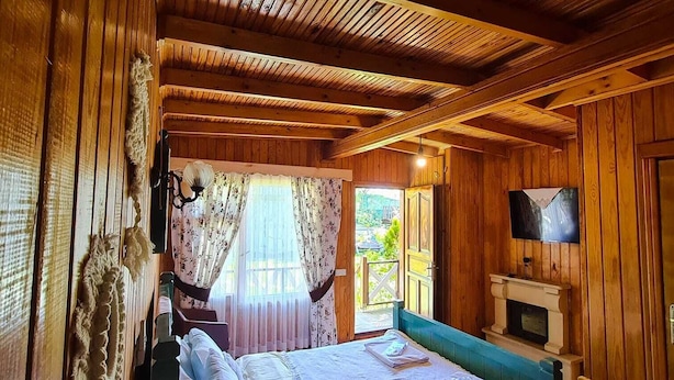Une chambre confortable dans un chalet en bois, avec un grand lit, une télévision et une cheminée.