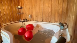 Une salle de bain avec un intérieur en bois, une baignoire dotée d’un robinet noir et une serviette blanche.