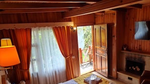 Une pièce chaleureuse en bois, avec un lit, une télévision et une cheminée.