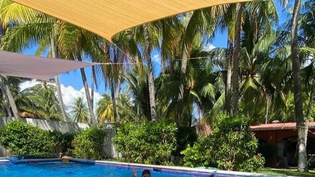 A swimming pool with clear blue water, surrounded by lush greenery and palm trees. - Paradise Bay (Puerto El Triunfo)
