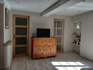 A room with a wooden cabinet, a television, and a framed picture on the wall. - Gîte le Milan, en Plein Cœur de la Magnifique Petite Ville de Florac (Florac-Trois-Rivières)