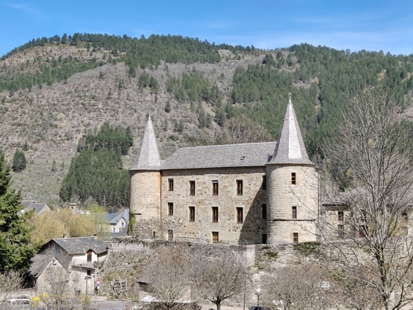 A stone building with two towers, surrounded by trees and hills. - Gîte le Milan, en Plein Cœur de la Magnifique Petite Ville de Florac (Florac-Trois-Rivières)