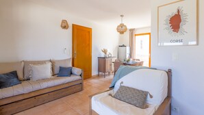 Un salon confortable avec un canapé, un lit, une armoire en bois et une carte encadrée accrochée au mur.