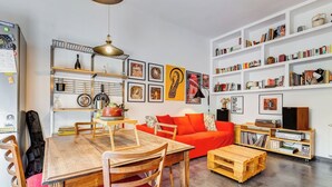 Un salón moderno con una mesa de comedor de madera, un sofá rojo y estanterías llenas de libros y objetos decorativos.