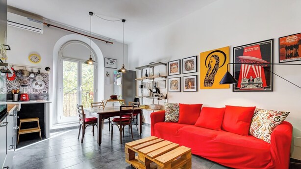 Una sala de estar moderna con un sofá rojo, una mesa de centro de madera y un comedor con una mesa y sillas de madera.