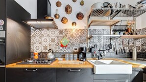 Una cocina moderna con estufa a gas, cafetera y una variedad de utensilios en la pared.