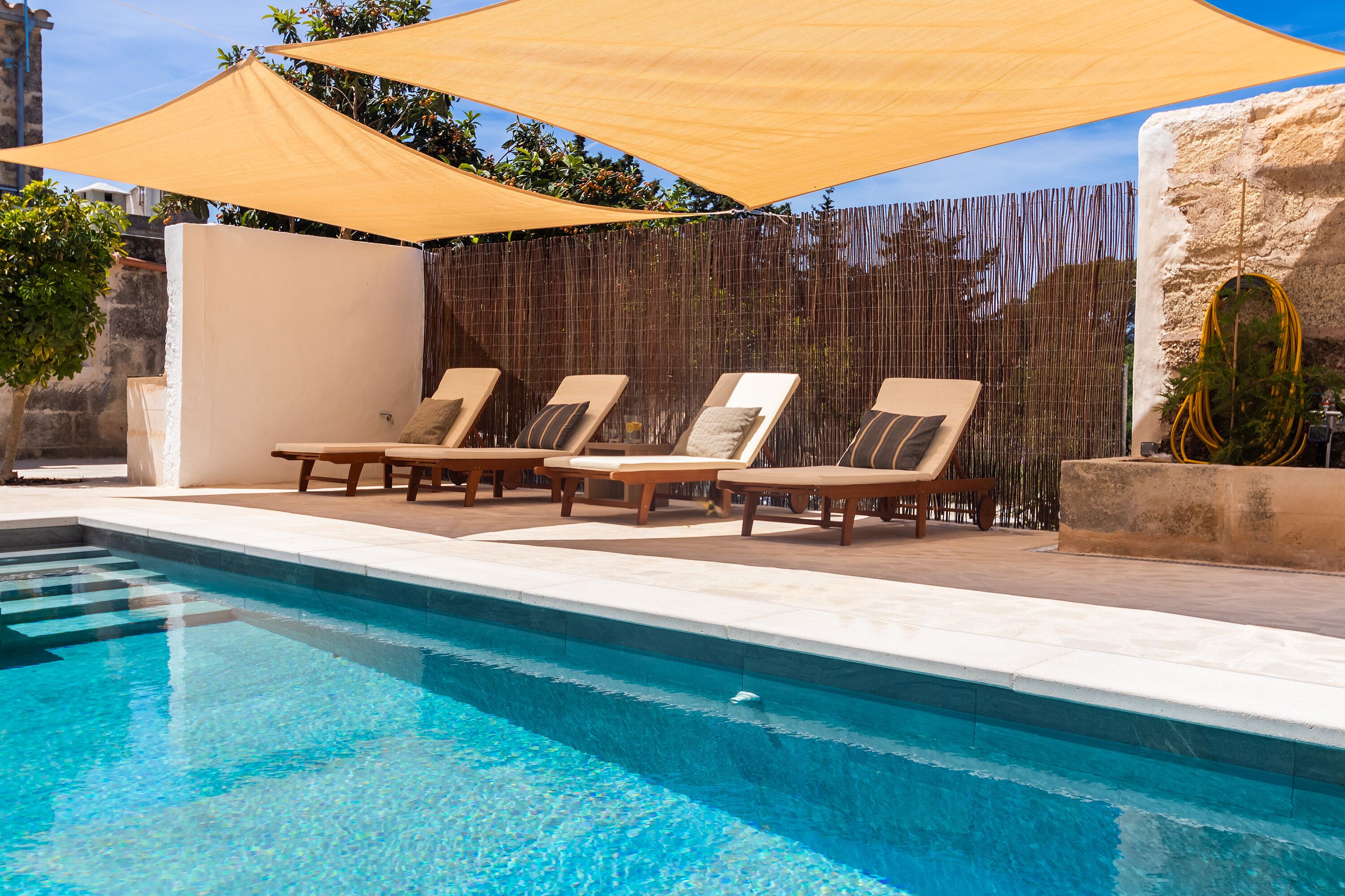 Une piscine avec des chaises longues et un auvent.