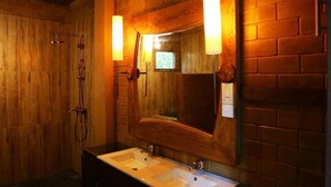 Une salle de bain avec des murs en bois, un grand miroir et deux lavabos.