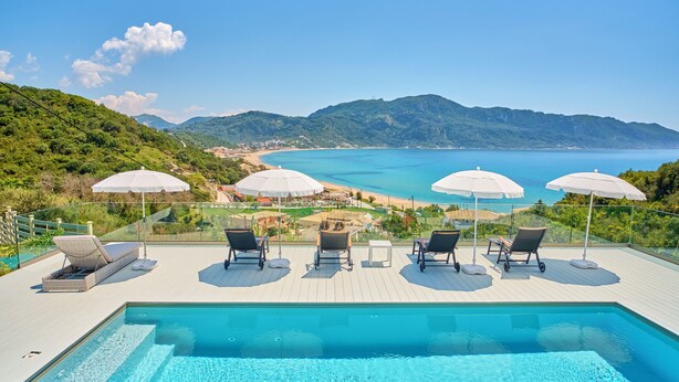 Ein Poolbereich mit Liegestühlen und Sonnenschirmen mit Blick auf eine Küstenlandschaft.