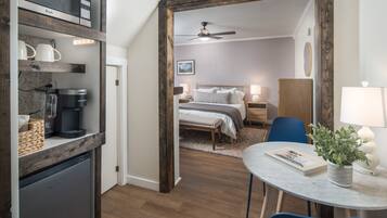 A compact room with a bed, bedside tables, a desk with a chair, a small refrigerator, and a microwave.