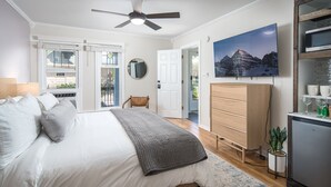 A bedroom with a bed, a ceiling fan, a dresser, a TV, and a view of the outdoors. - The Victorian Inn Blowing Rock (Blowing Rock)