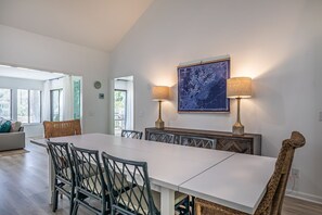 Un coin repas avec une table blanche, des chaises noires et deux lampes. Une grande carte est accrochée au mur, au-dessus de la table.