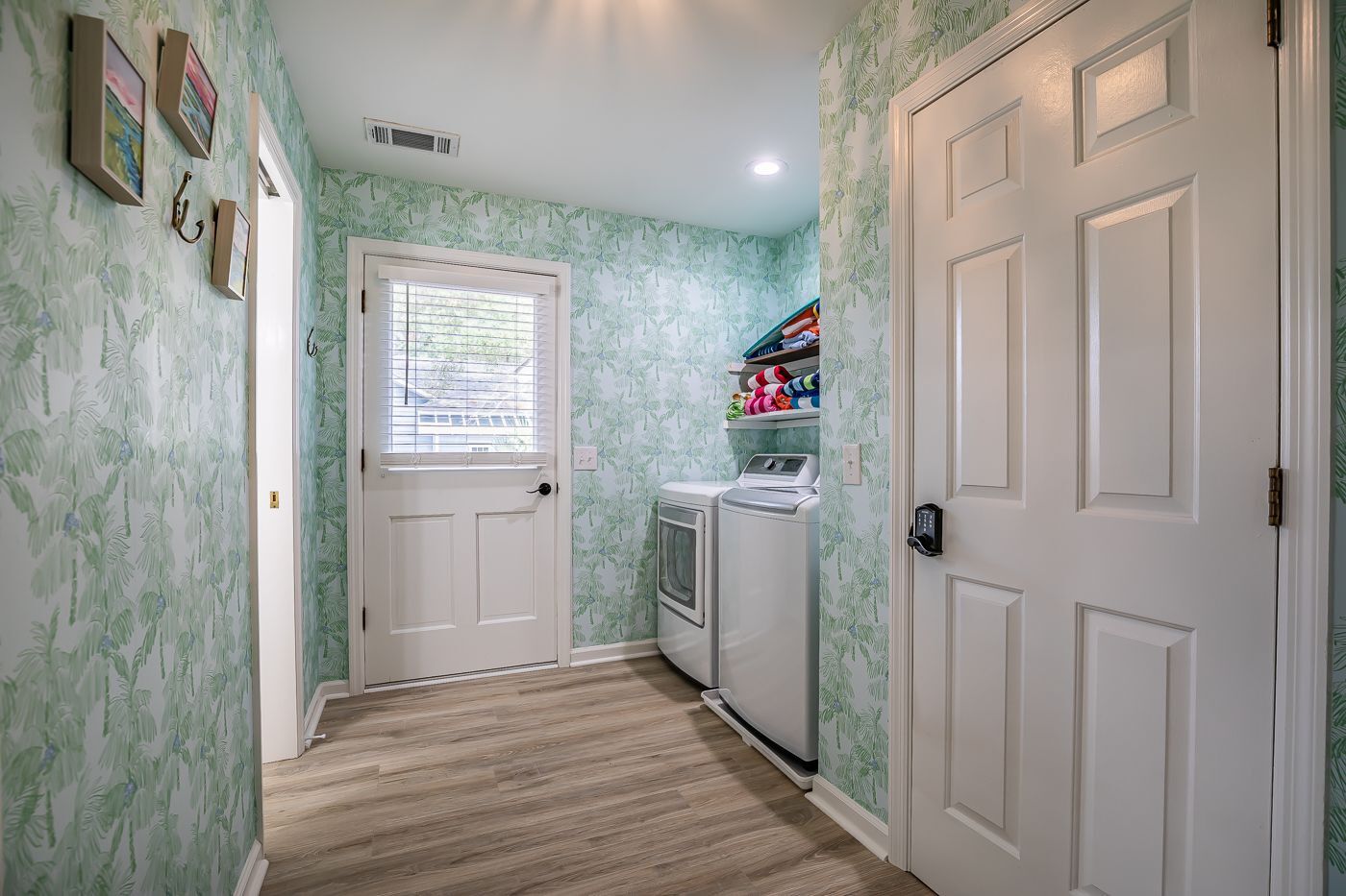 A laundry room with a washing machine, a dryer, and a shelf with folded clothes.