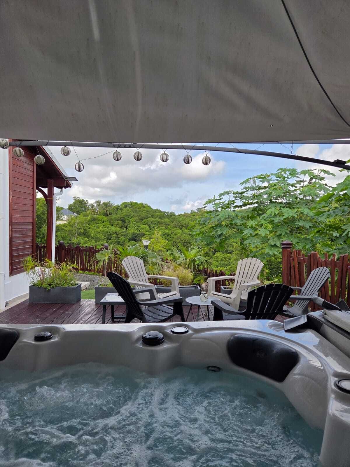 A hot tub area with chairs and a view of a lush garden.