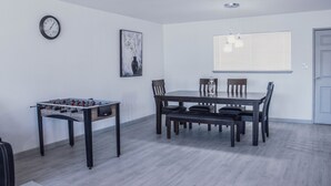 A dining area with a wooden table and chairs, a clock on the wall, and a window with blinds. - Beautiful and cozy house in Las Vegas (Las Vegas)