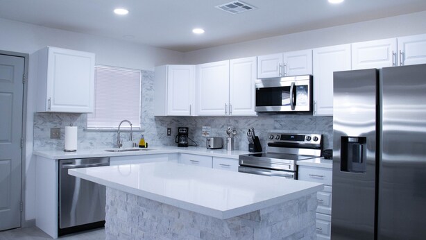 A modern kitchen with white cabinets, stainless steel appliances, and a marble island. - Beautiful and cozy house in Las Vegas (Las Vegas)