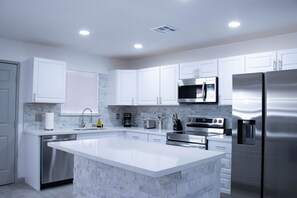 Una cocina moderna con armarios blancos, electrodomésticos de acero inoxidable y una isla de mármol.