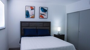 A bedroom with a bed, a nightstand, a lamp, and two abstract paintings on the wall. - Beautiful and cozy house in Las Vegas (Las Vegas)