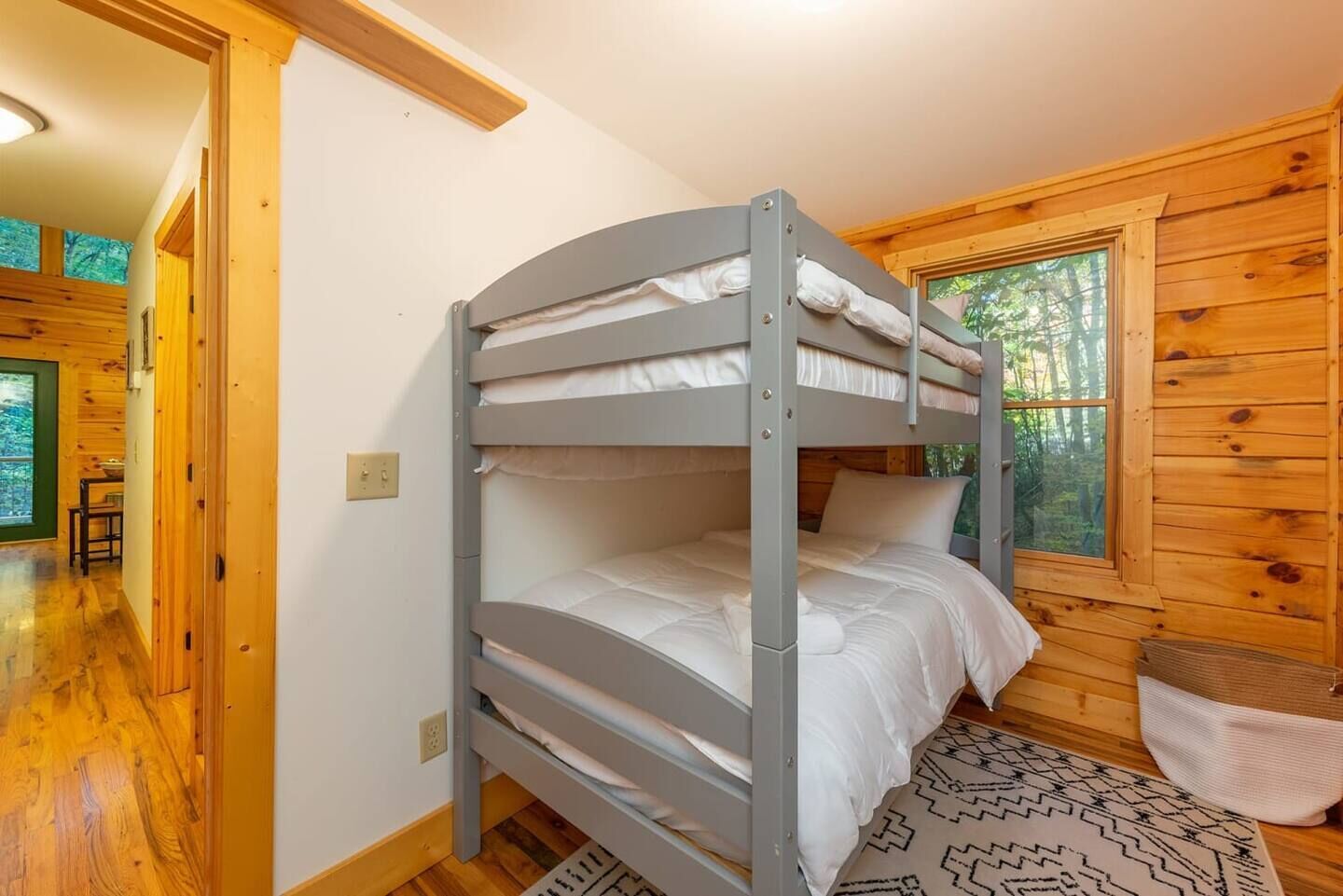 A bunk bed in a cabin with wooden walls and a window.