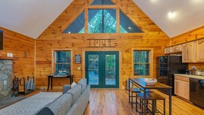 A log cabin with a loft bedroom, a dining area, and a kitchen. - Creekside Cabin • Hot Tub • Decks (Maggie Valley)