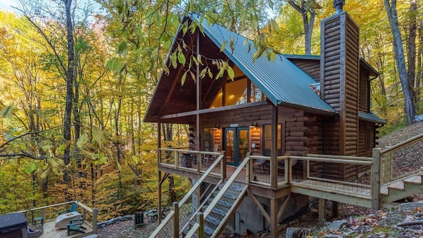 A log cabin with a wooden deck and stairs leading to a covered porch. - Creekside Cabin • Hot Tub • Decks (Maggie Valley)