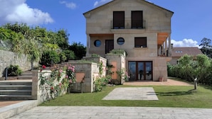 A two-story house with a stone facade, a central entrance with glass doors, and a small balcony on the upper floor. - Cozy Nest w/private garden next to vineyards and great wineries (Cambados)