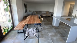 A modern kitchen with a wooden dining table, a built-in island, and a seating area with a sofa and chairs. - Cozy Nest w/private garden next to vineyards and great wineries (Cambados)