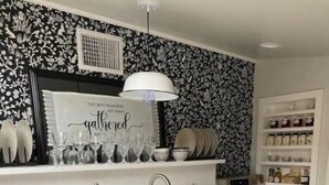 A kitchen with a white countertop, stainless steel appliances, a built-in oven, and a wall-mounted shelf with jars.