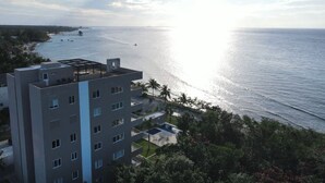 Un edificio moderno con varios pisos, una terraza en la azotea y vistas al océano.
