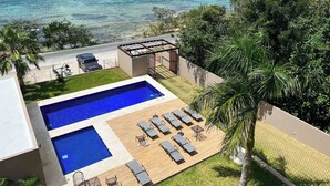 Una piscina en la azotea con sillones de descanso y vistas al océano.