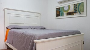 Ein Schlafzimmer mit einem weißen Bett, grauer Bettwäsche und einem Kissen.