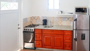 Eine kompakte Küche mit Gasherd, Backofen und Kühlschrank, mit gefliestem Rücksprüher und Holzschränken.