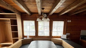 Une pièce moderne en bois, dotée d’une table centrale, de bancs intégrés et de grandes fenêtres.