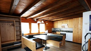 L’intérieur d’une cabane en bois comprend une cuisine, un coin repas avec des bancs et une étagère intégrée.
