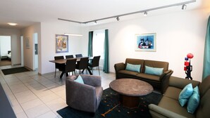 A modern living room with a sofa, armchairs, a coffee table, and a dining area with chairs and a table. - Cristal by Interhome (Saas-Fee)