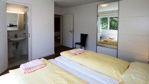 A bedroom with two beds, a bathroom with a sink, and a mirror reflecting the room. - Cristal by Interhome (Saas-Fee)
